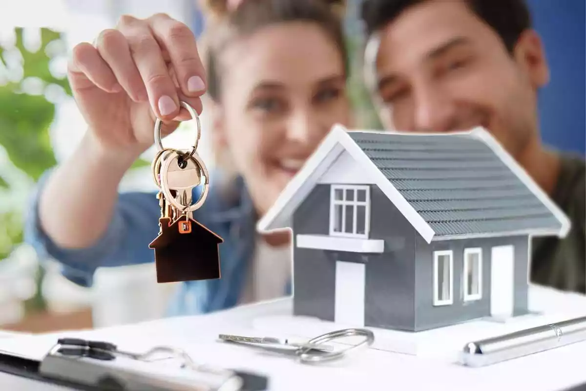 Montaje con una imagen de una pareja sujetando unas llaves y una casa de juguete encima de un contrato hipotecario